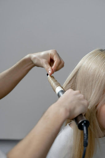 Women getting her hair curled using a curling wand