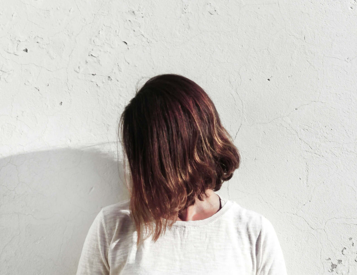 women who has repaired her damaged hair standing against a wall 